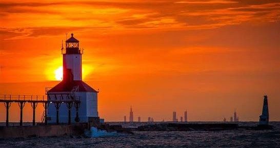 The Michigan City lighthouse at sunset, the Chicago skyline on the horizon